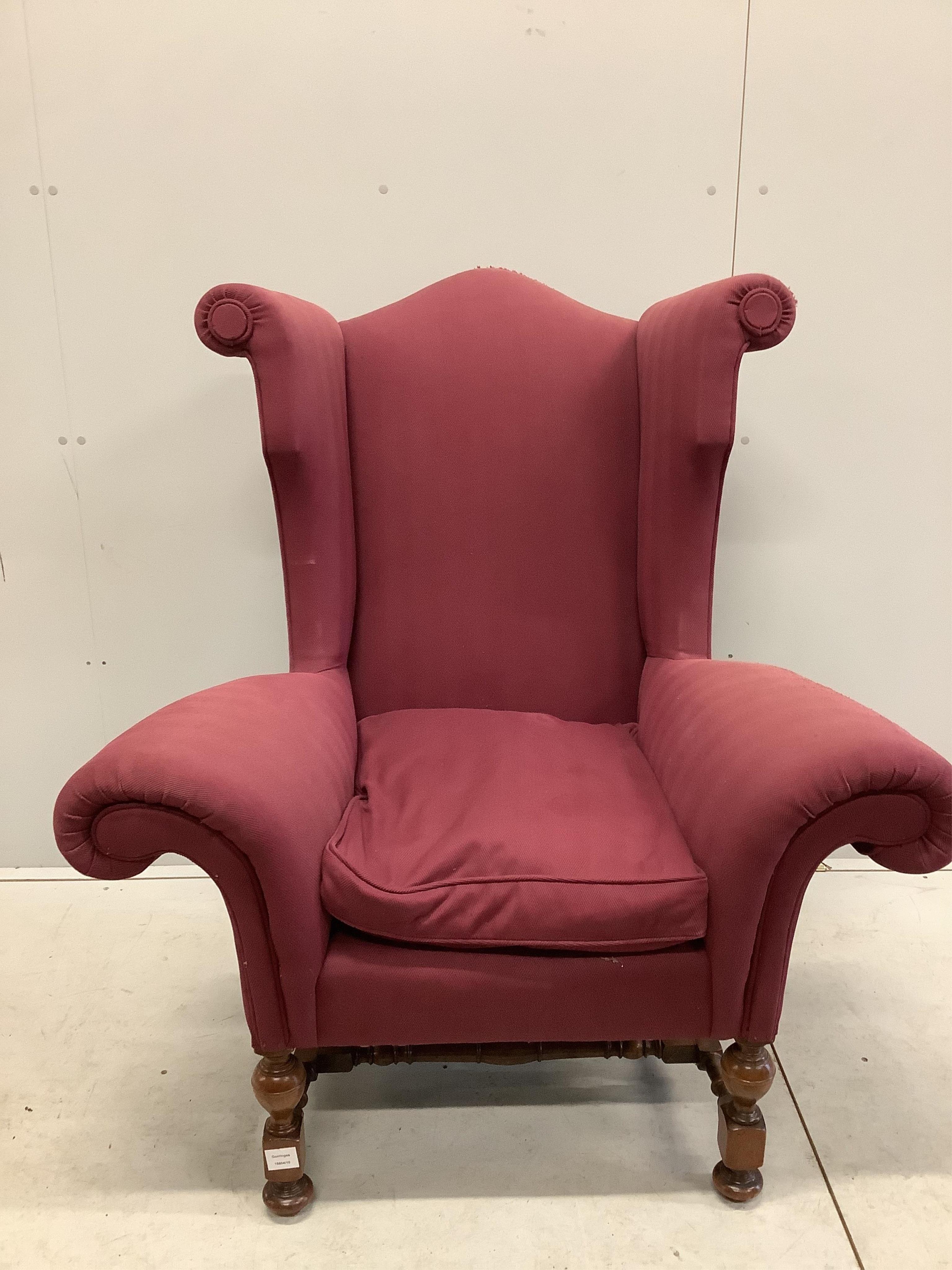 A Queen Anne revival wing armchair with wide scroll arms on turned walnut underframe, width 106cm, depth 70cm, height 120cm. Condition - fair, upholstery poor